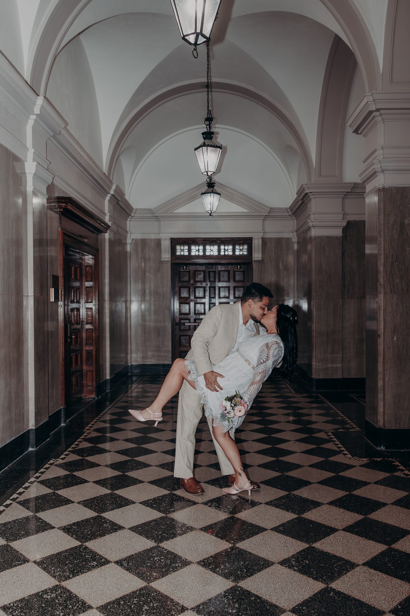 Caleb dipping Karlee for a kiss in the vaulted courthouse hallway