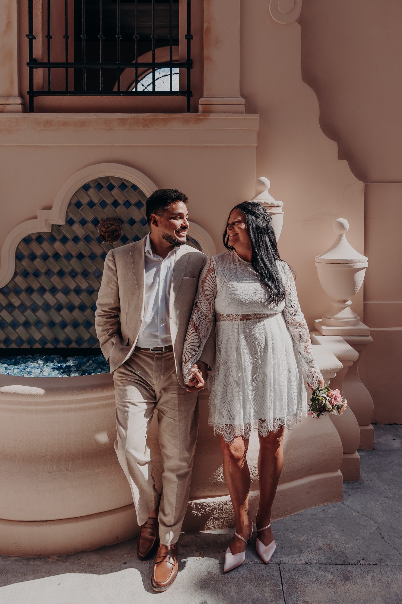 Karlee and Caleb holding hands and smiling near the Sarasota fountain courtyard