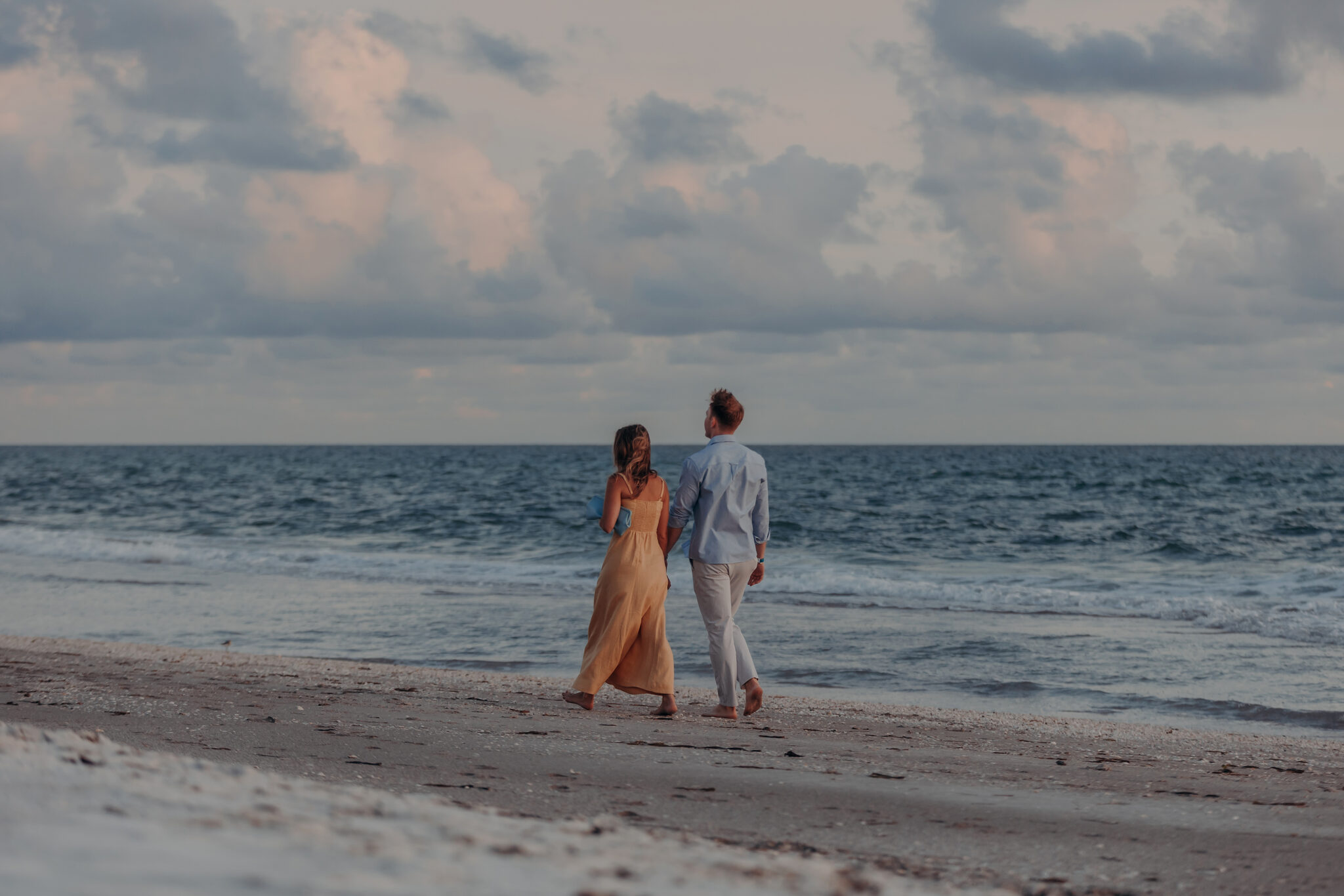 Michael and Regan walk hand in hand along the beach on Longboat Key