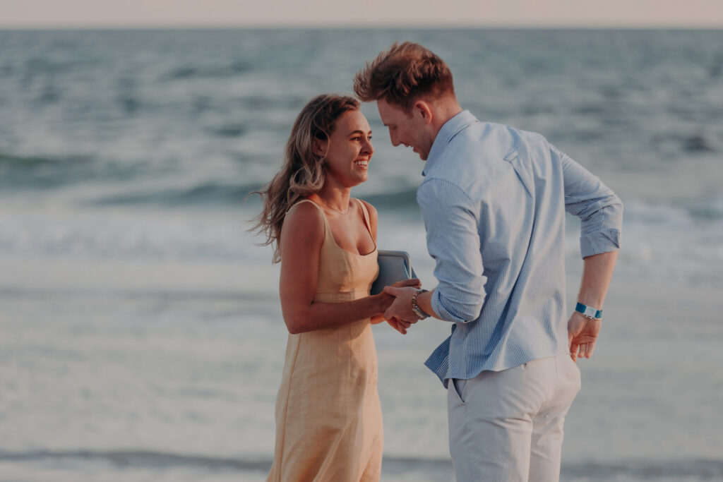 Michael and Regan embrace at sunset following their surprise beach proposal