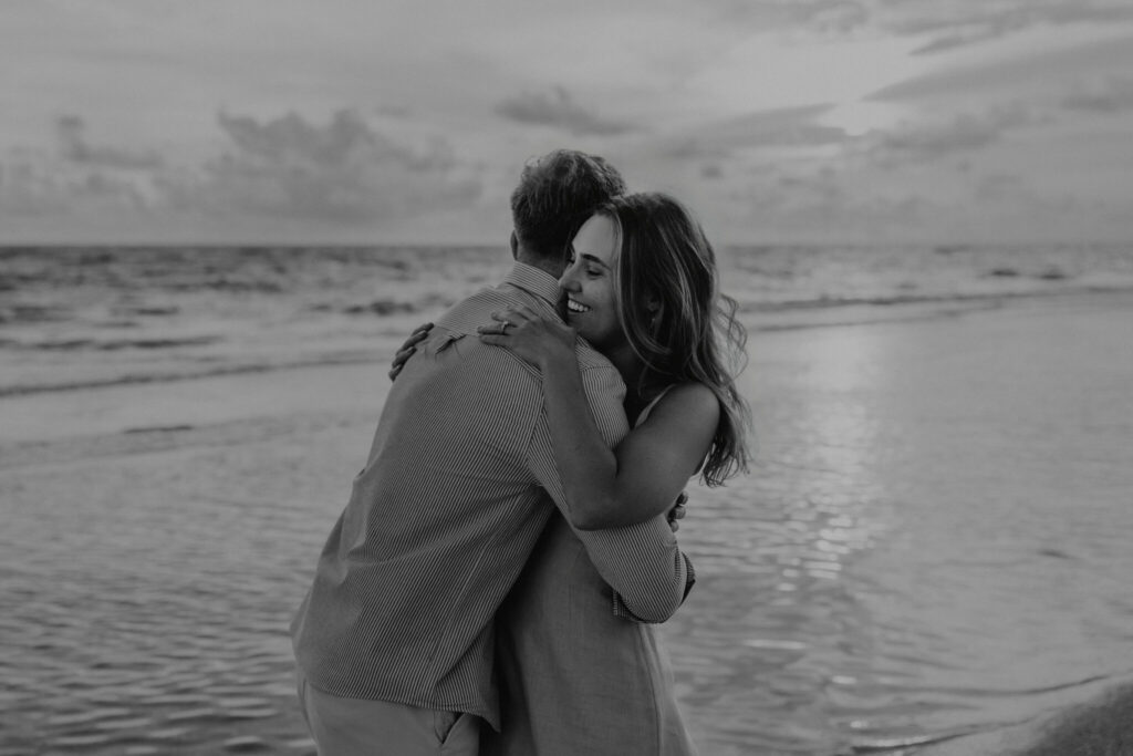Black and white portrait of Michael and Regan embracing on the beach