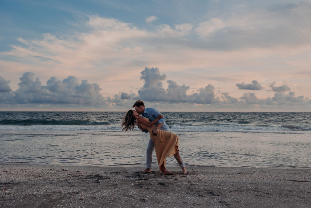 Michael and Regan embrace at sunset following their surprise beach proposal