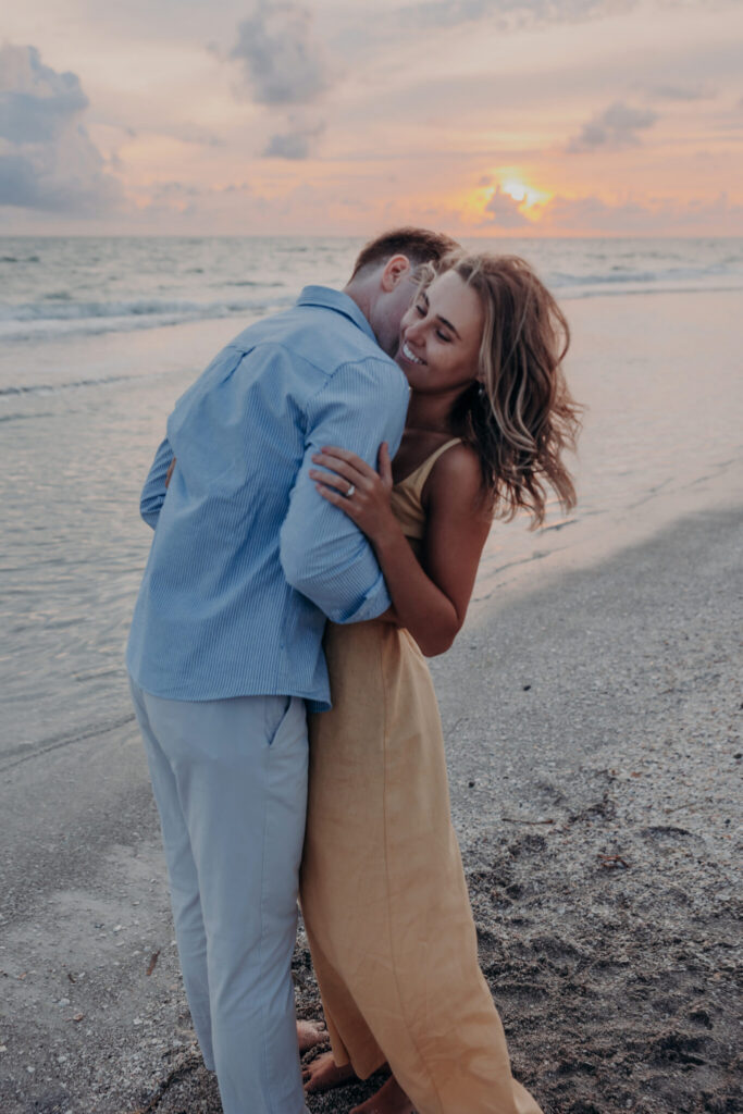 Michael and Regan embrace at sunset following their surprise beach proposal