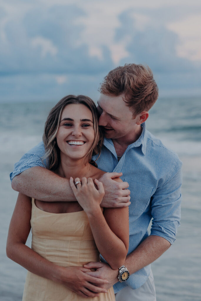 Michael and Regan embrace at sunset following their surprise beach proposal